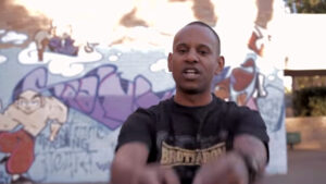 Brotherblack rapping in front of wall with graffiti
