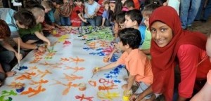 Children painting colourful stick figures on large canvas