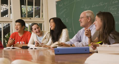 Laughing students and teacher sitting at table