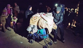 A man and his wife use a stroller to carry essential possessions across the border at night.