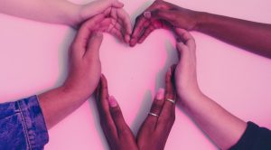 Hands from diverse cultural backgrounds making a heart shape